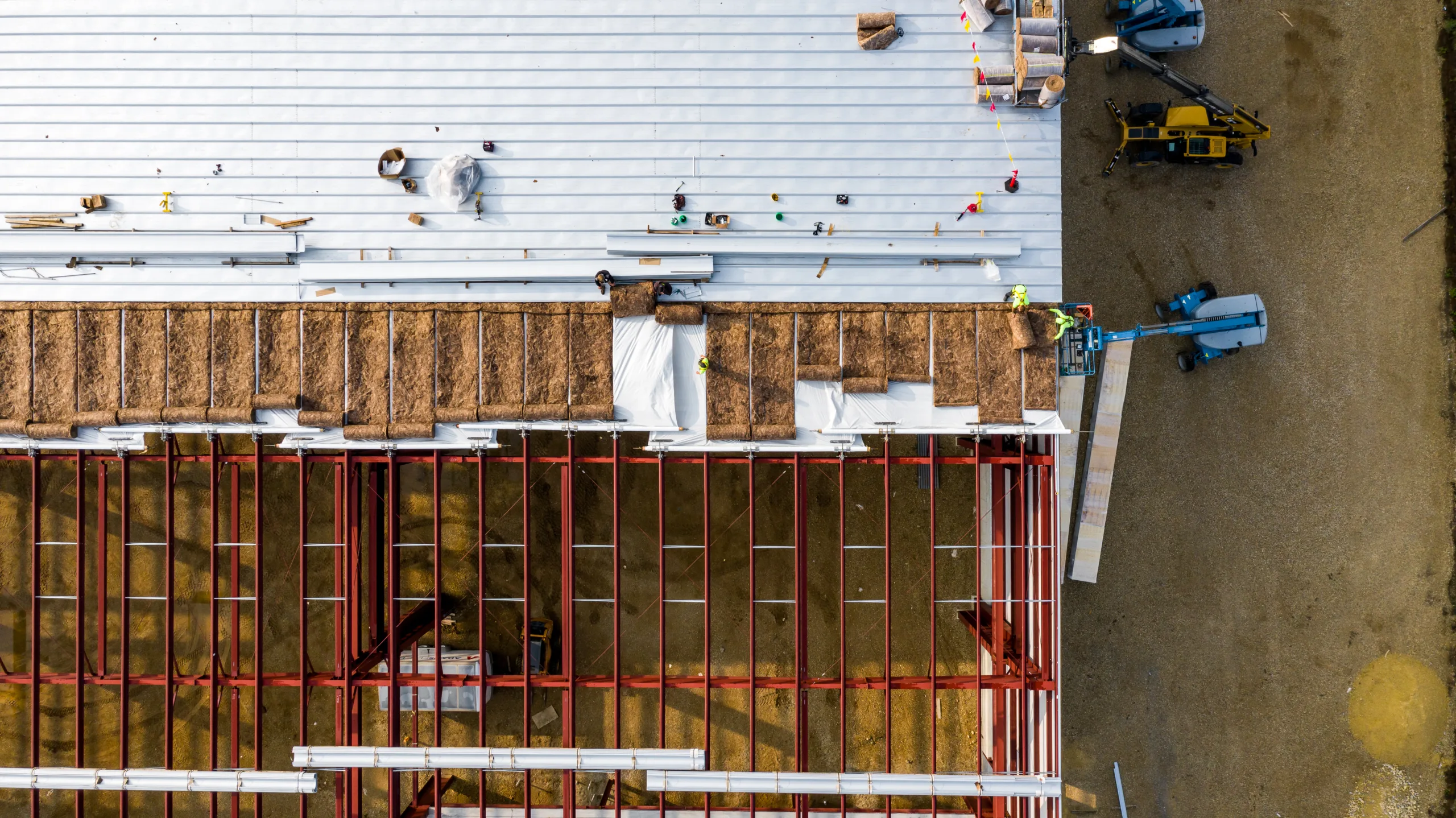 Construction Workers Installing Roof Panels On A Warehouse.